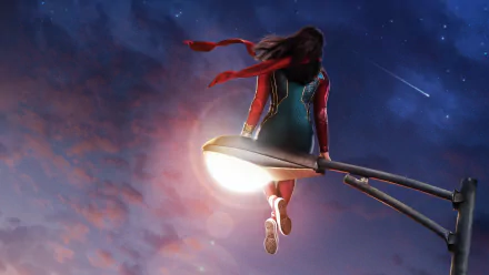 Ms. Marvel (TV show) perched on a glowing streetlamp at dusk, red scarf trailing against a starry sky — HD PC desktop wallpaper/background.