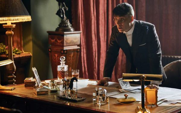 4K Ultra HD PC wallpaper: sharply dressed 1920s-style man leans over an ornate desk in a dim, smoky period office, vintage glassware and moody lighting creating a tense atmosphere.