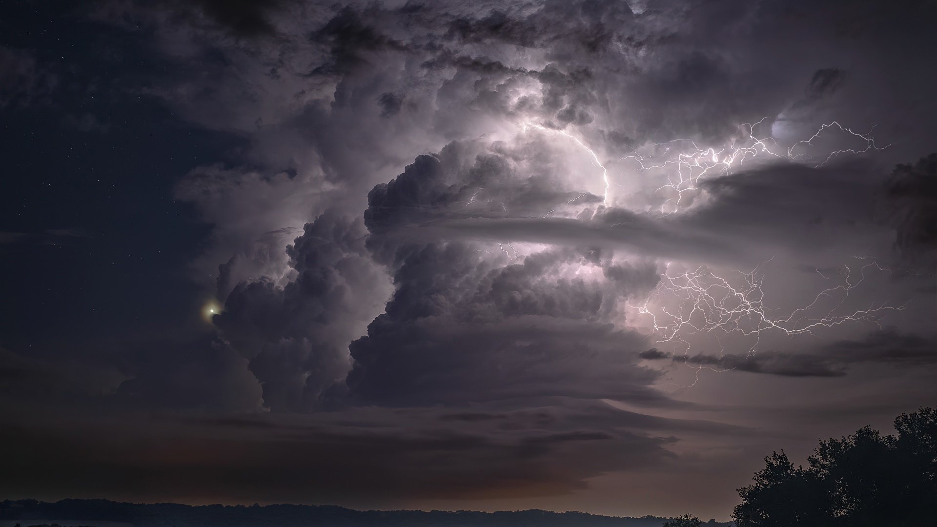 HD desktop wallpaper showcasing a dramatic storm with lightning illuminating dense clouds over a dark landscape in nature.