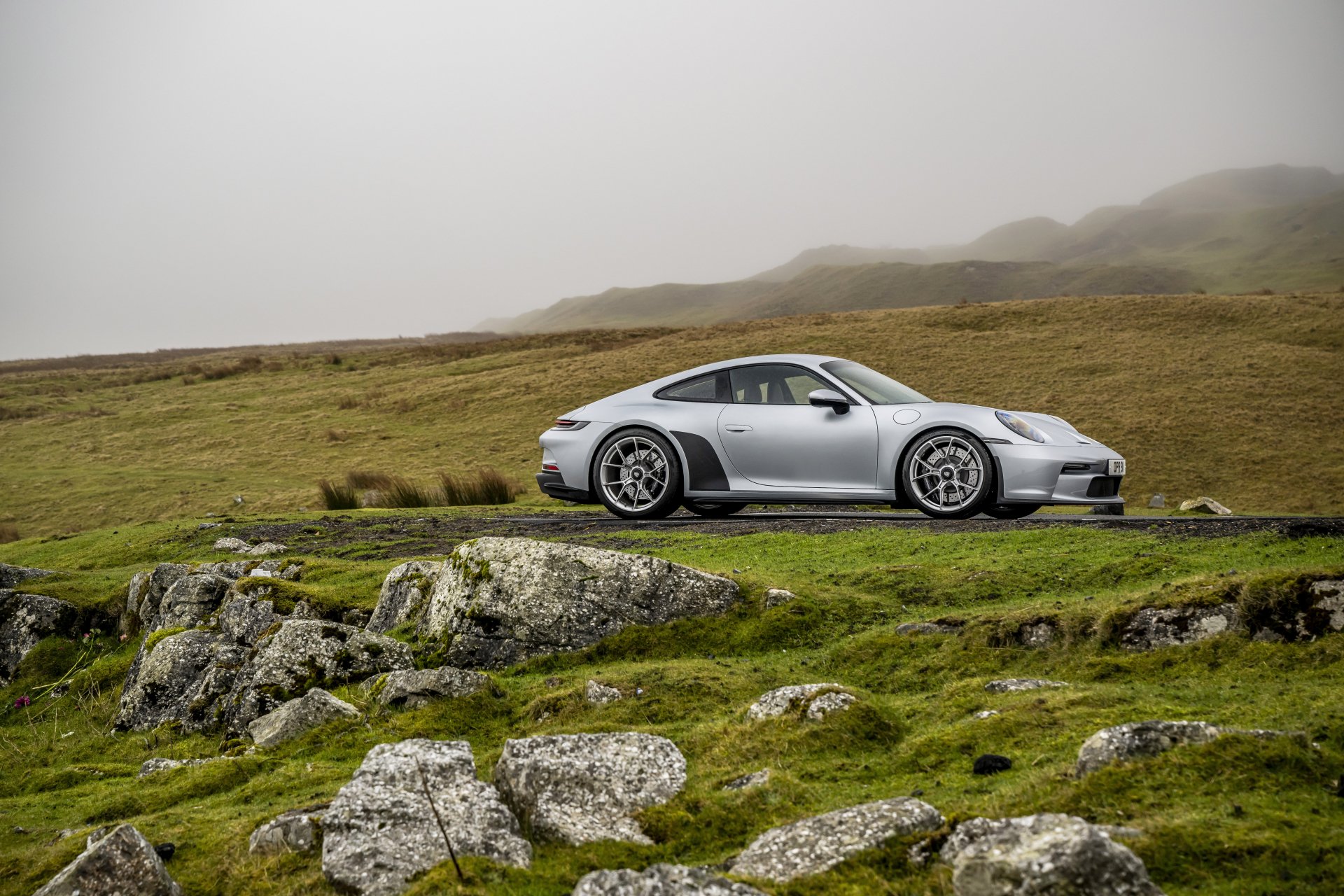 Silver Porsche 911 GT3 parked on a grassy cliffside under a misty sky — 8K Ultra HD PC desktop wallpaper/background.