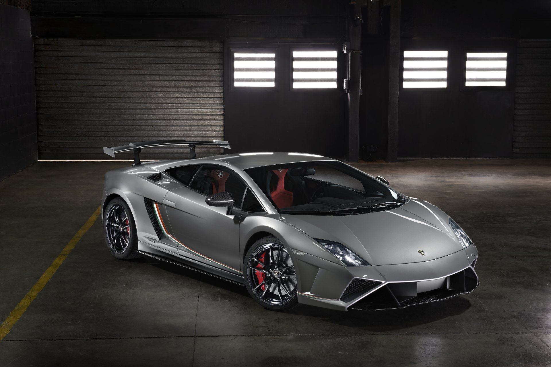 8K Ultra HD PC desktop wallpaper background: silver Lamborghini Gallardo sports vehicle parked in a dim industrial garage, red interior and aerodynamic rear wing visible.