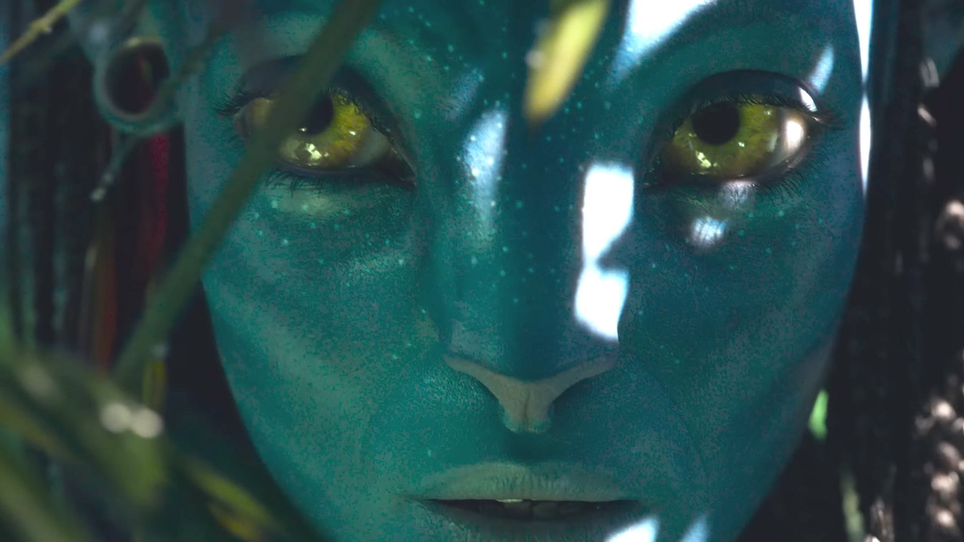 Close-up HD desktop wallpaper of Neytiri from the movie Avatar: The Way of Water, showcasing her detailed facial features and glowing yellow eyes.