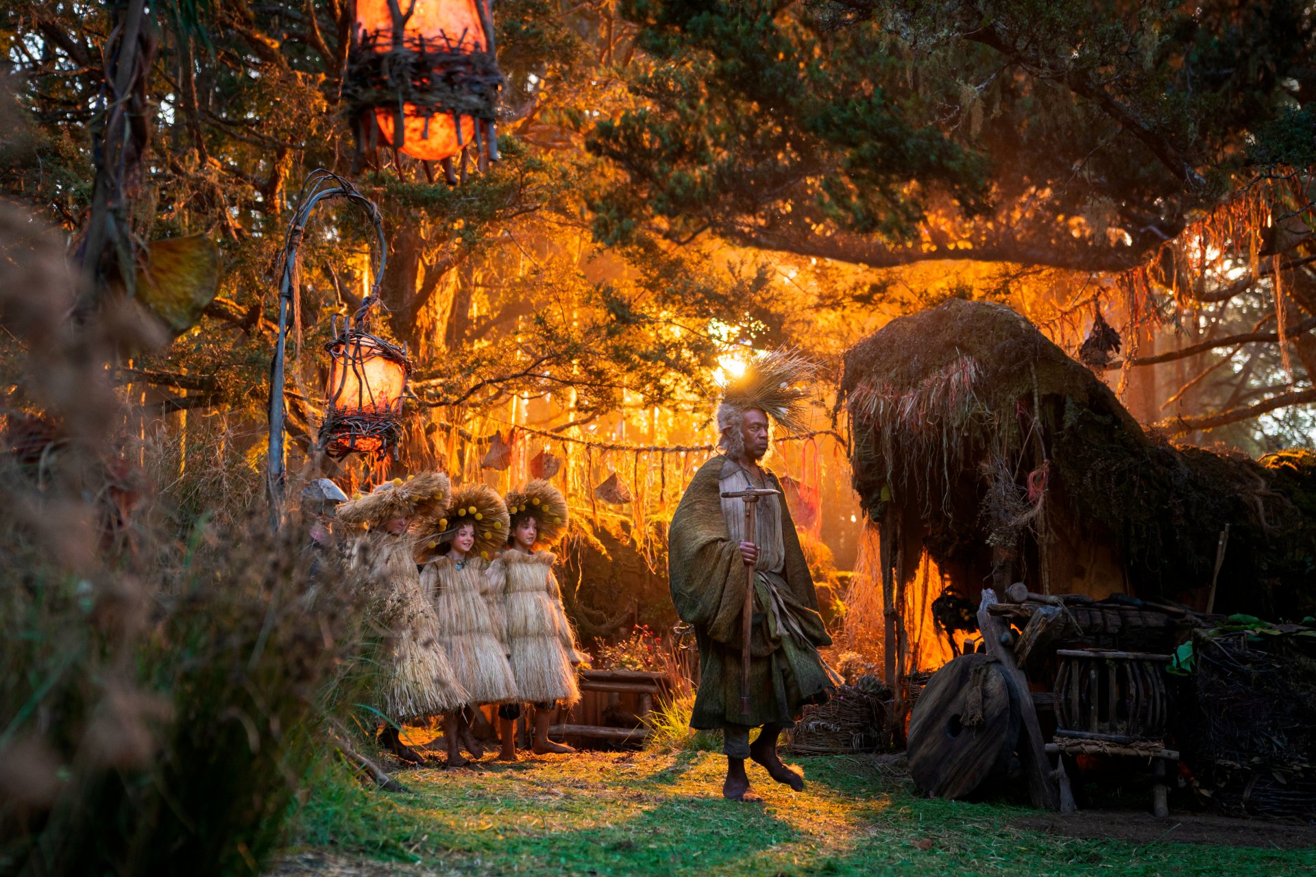 A detailed 4K Ultra HD desktop wallpaper from the TV show The Lord of the Rings: The Rings of Power featuring a woodland scene with characters and glowing lanterns.