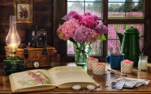 Photography still life 4K Ultra HD PC Desktop Wallpaper and Background — rustic wooden table with open botanical book, pink hydrangeas in a vase, vintage camera, lantern, mugs and a window view of purple fields.