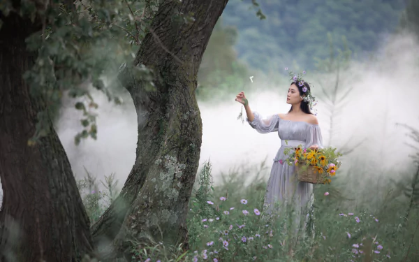 4K Ultra HD wallpaper of an Asian woman in a flowing white dress and flower crown, holding a basket of sunflowers, standing in a misty forest clearing.