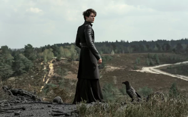 2K Quad HD PC desktop wallpaper: moody The Sandman TV show scene — a dark-clad figure on a windswept hillside with a raven, winding dirt path and distant treeline.