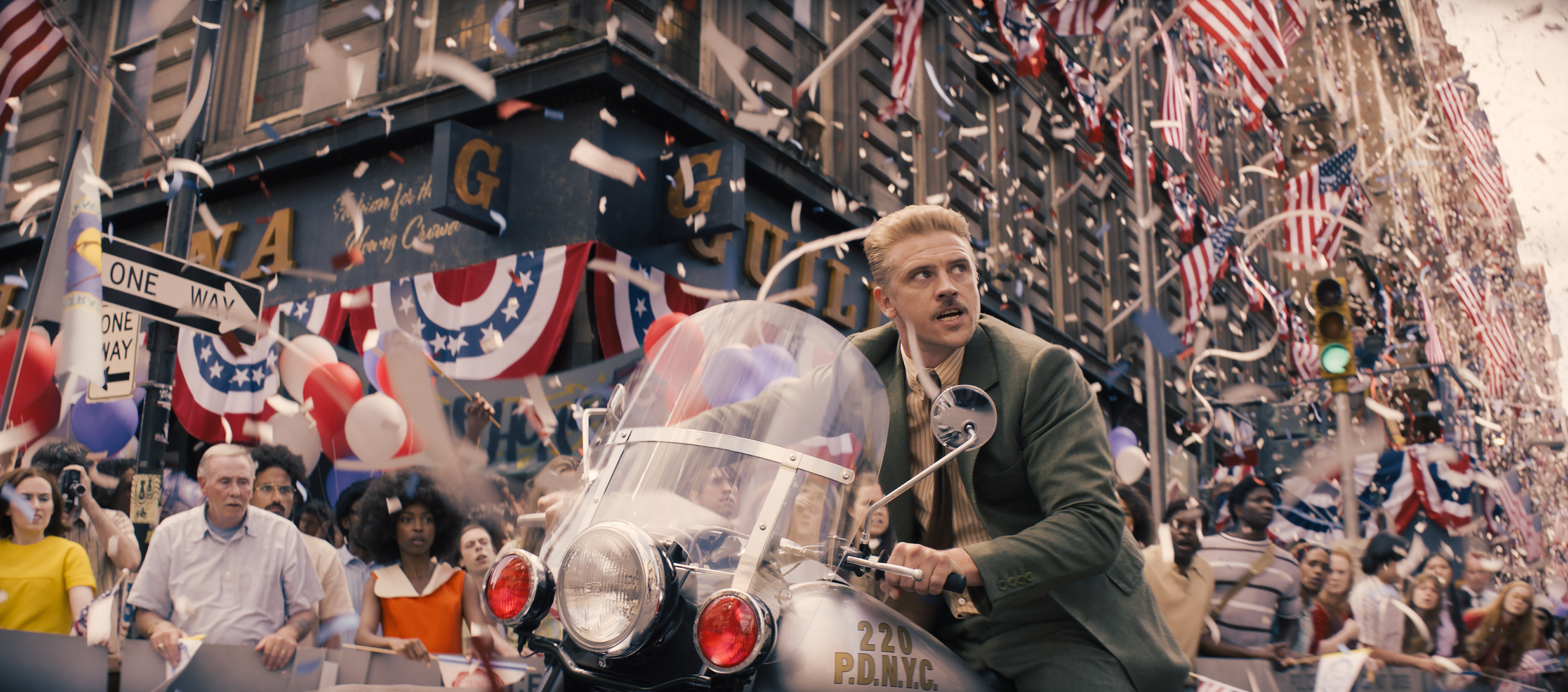 HD wallpaper of Indiana Jones and the Dial of Destiny featuring a character in a festive parade scene with American flags and confetti, ideal for desktop background.