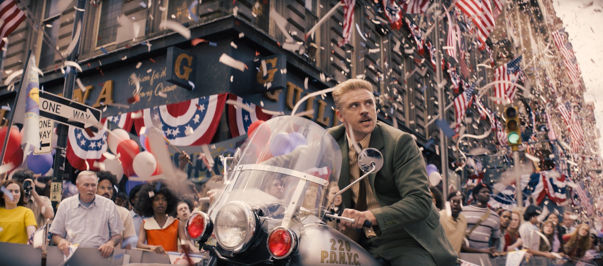 HD desktop wallpaper from Indiana Jones and the Dial of Destiny featuring a scene with a character in a parade, surrounded by American flags and confetti.