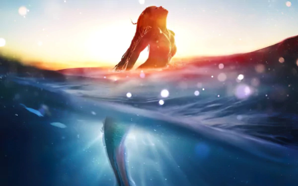 A 4K Ultra HD PC desktop wallpaper of Ariel, the mermaid from The Little Mermaid (2023), emerging from the water at sunset with shimmering light reflections.