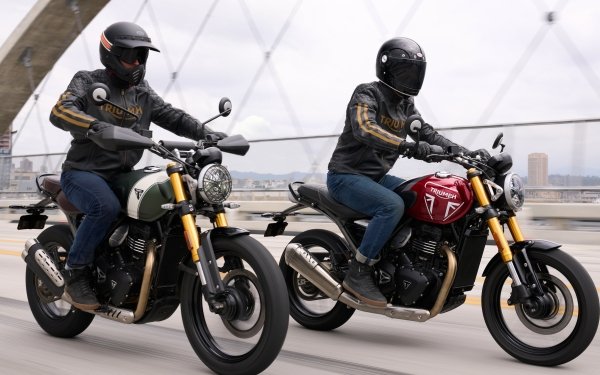 Two riders on Triumph motorcycles, specifically a Triumph Speed 400 and a Triumph Scrambler 400 X, cruising across a bridge, suitable as a high-definition desktop wallpaper or background.
