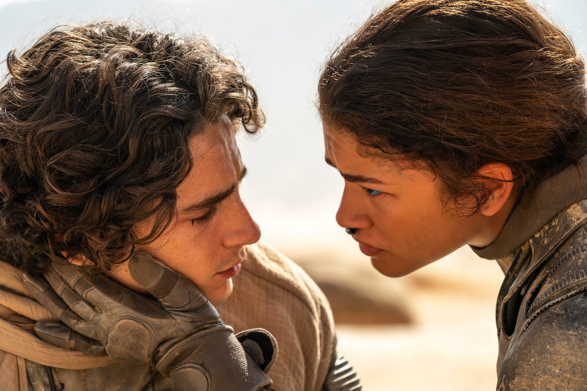 HD wallpaper featuring two characters from Dune: Part Two in a close-up emotional scene, set against a desert backdrop.