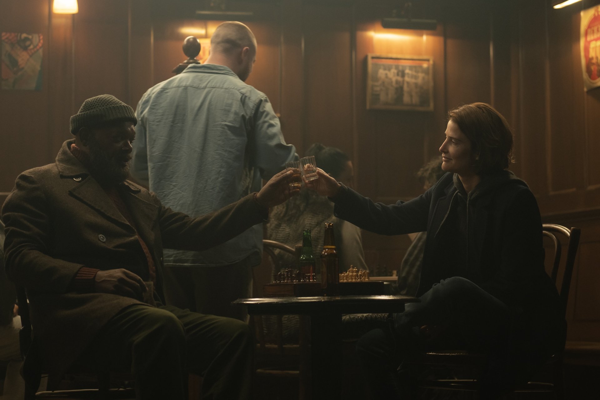 HD desktop wallpaper of a scene from Secret Invasion featuring two people sitting and shaking hands in a dimly lit room.