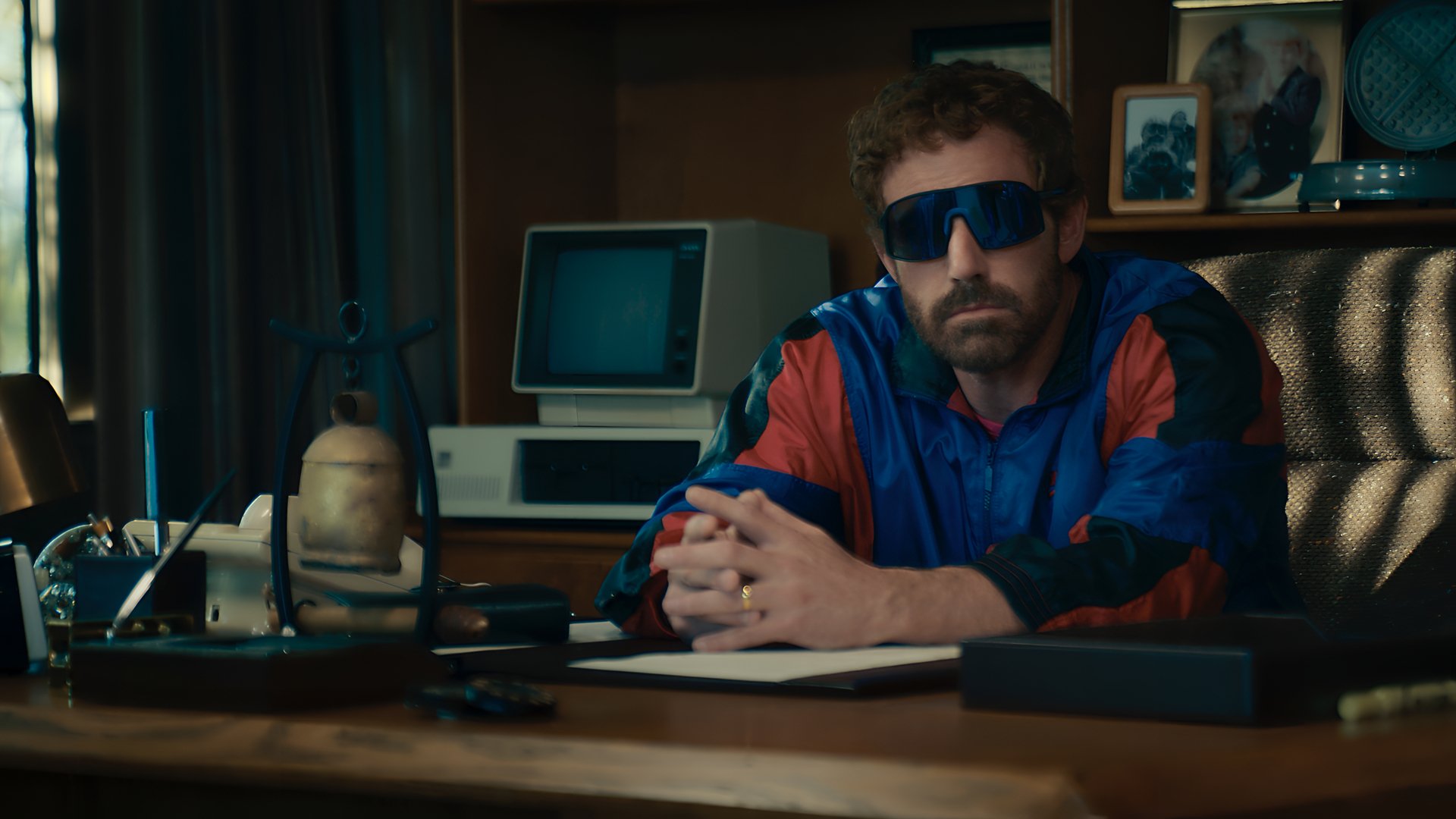 Man in sunglasses sitting at a desk with vintage computer and phone, evoking a retro vibe for an HD desktop wallpaper.