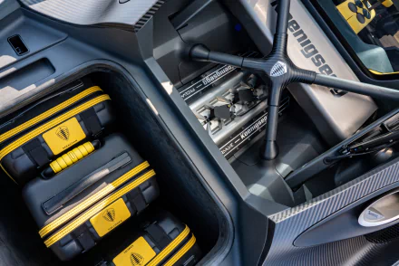 HD desktop wallpaper showing a detailed view of the interior and engine components of the Koenigsegg Gemera with carbon fiber finishes and yellow accents.