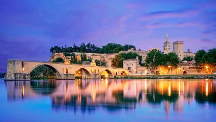 HD desktop wallpaper showing the man-made Pont Saint-Bénézet bridge over the Rhône River in Avignon, with vibrant reflections at twilight.