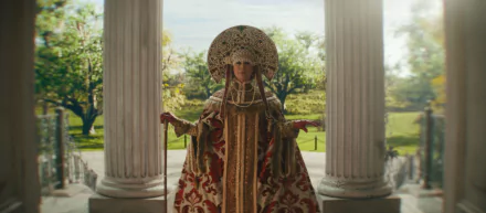 HD desktop wallpaper featuring Jamie Lee Curtis in an ornate costume from the movie Haunted Mansion, posed between white pillars with a scenic garden background.