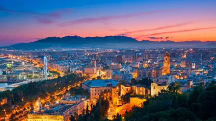 A vibrant 4K Ultra HD cityscape of Malaga at sunset, showcasing man-made buildings and landmarks under a colorful sky, designed as a PC desktop wallpaper.