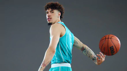 Charlotte Hornets basketball player in turquoise jersey spinning a basketball on his finger against a grey background, HD desktop wallpaper.