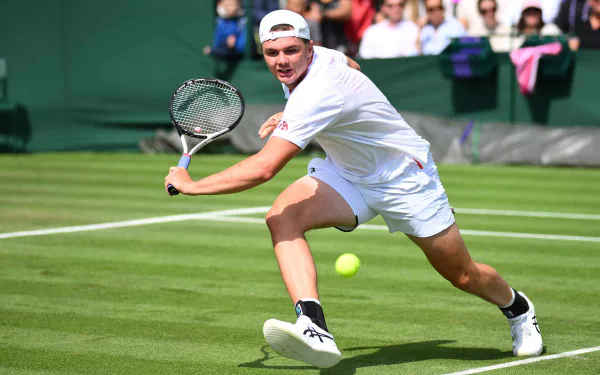 Dominic Stricker in action at Wimbledon 2023, poised to hit a tennis ball, captured as an HD desktop wallpaper.