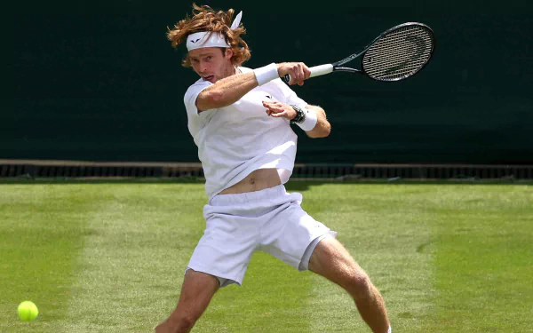 HD wallpaper featuring an intense tennis action shot at Wimbledon 2023, with a male player in mid-swing on the grass court.