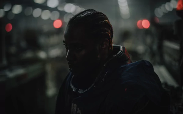 HD wallpaper featuring a still of a character from The Creator (2023) in a dimly lit industrial setting, providing a moody background for desktops.