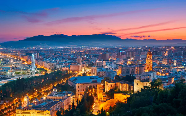 A vibrant 4K Ultra HD cityscape of Malaga at sunset, showcasing man-made buildings and landmarks under a colorful sky, designed as a PC desktop wallpaper.
