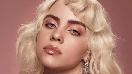 HD wallpaper of a person with blonde wavy hair and striking blue eyes, exuding a confident pose against a soft pink background.