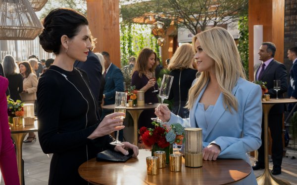 HD desktop wallpaper featuring two women from The Morning Show exchanging a conversation over drinks at a vibrant social event, perfect for a background theme.