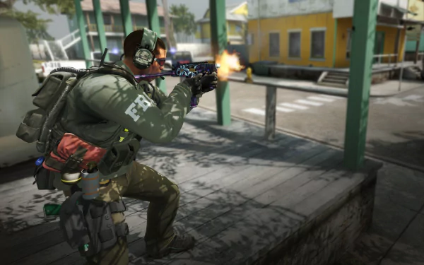 A soldier in tactical gear fires a weapon in a vibrant urban scene, representing intense gameplay in Counter-Strike 2. This high-definition image serves as a striking desktop wallpaper.