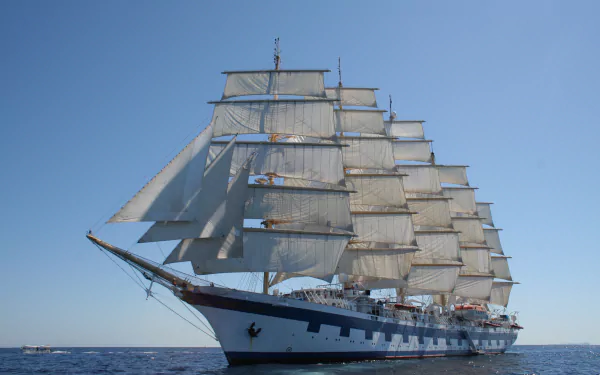 HD desktop wallpaper of a majestic sailing ship at sea with full sails against a clear blue sky.