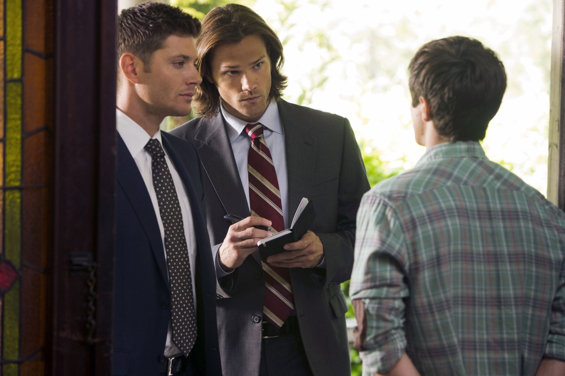 HD PC desktop wallpaper featuring Jensen Ackles and Jared Padalecki as Dean and Sam Winchester from the TV show Supernatural in a focused conversation scene.