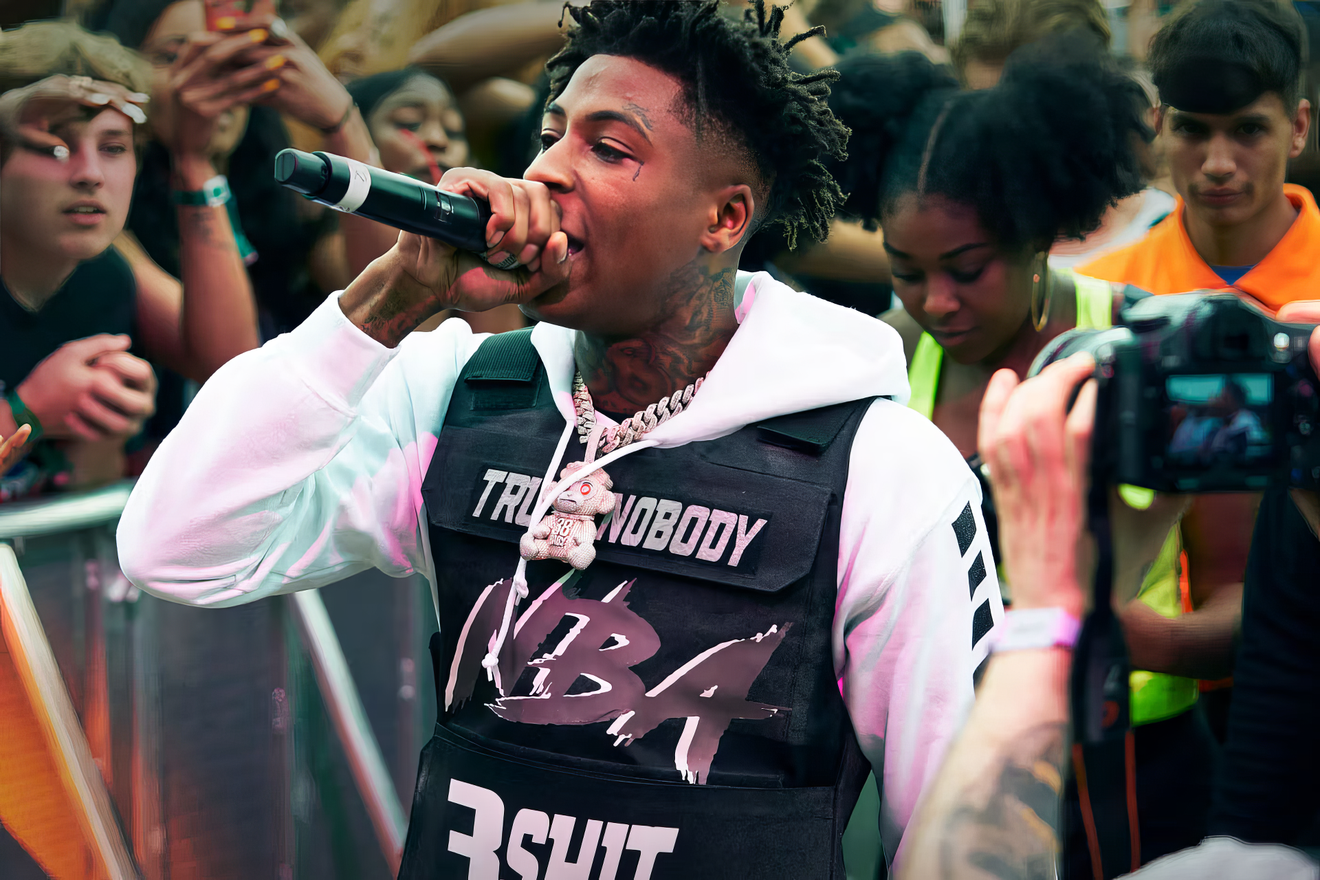 Music artist performing live in front of a crowd, captured as an HD desktop wallpaper and background tagged with YoungBoy Never Broke Again.