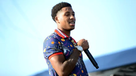 HD desktop wallpaper featuring a dynamic rapper on stage in a vibrant outfit, encapsulating the energy of the music scene.
