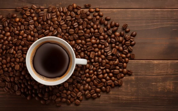 HD wallpaper featuring a cup of coffee surrounded by coffee beans on a wooden surface.