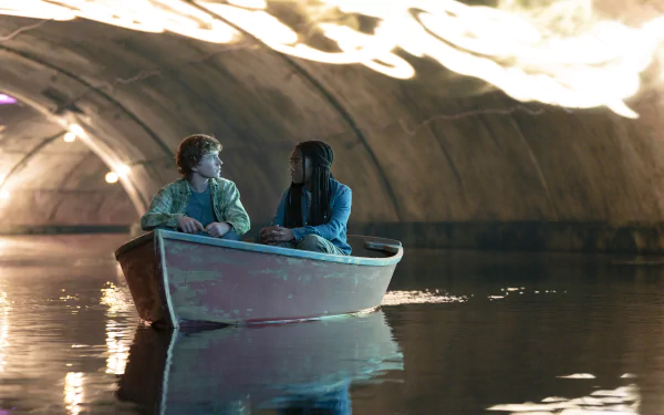 HD wallpaper of two characters from Percy Jackson and the Olympians TV show in a boat, with a mystical cave background.