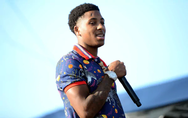 HD desktop wallpaper featuring a dynamic rapper on stage in a vibrant outfit, encapsulating the energy of the music scene.