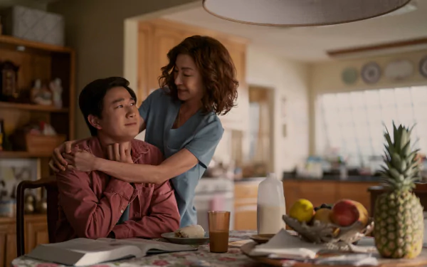 HD wallpaper featuring a tender moment from the TV show The Brothers Sun with a woman embracing a man from behind in a warmly lit kitchen setting.