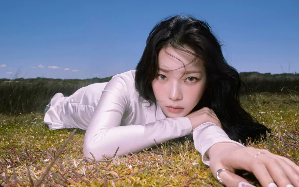 Karina lies on grass under a clear blue sky in this 4K Ultra HD PC desktop wallpaper and background.