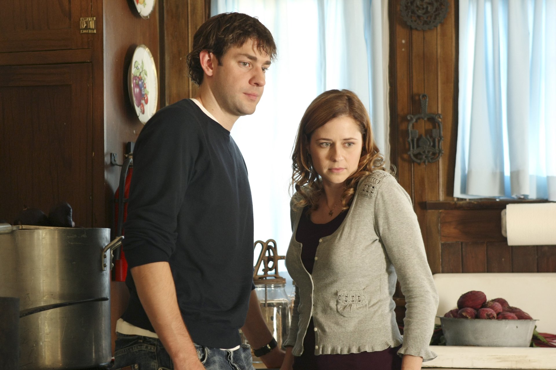 Jim Halpert and Pam Beesly, portrayed by John Krasinski and Jenna Fischer, stand together in a cozy kitchen setting from the TV show The Office (US).
