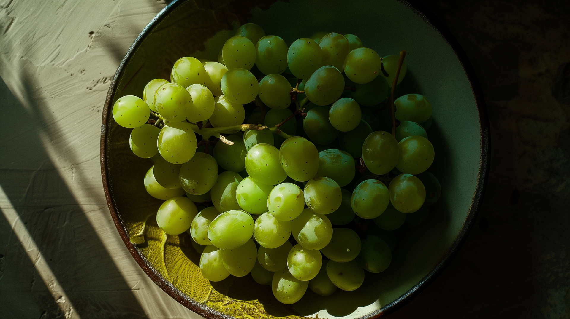 A close-up of fresh green grapes in a bowl, beautifully illuminated, creating a vibrant and refreshing HD desktop wallpaper background. 