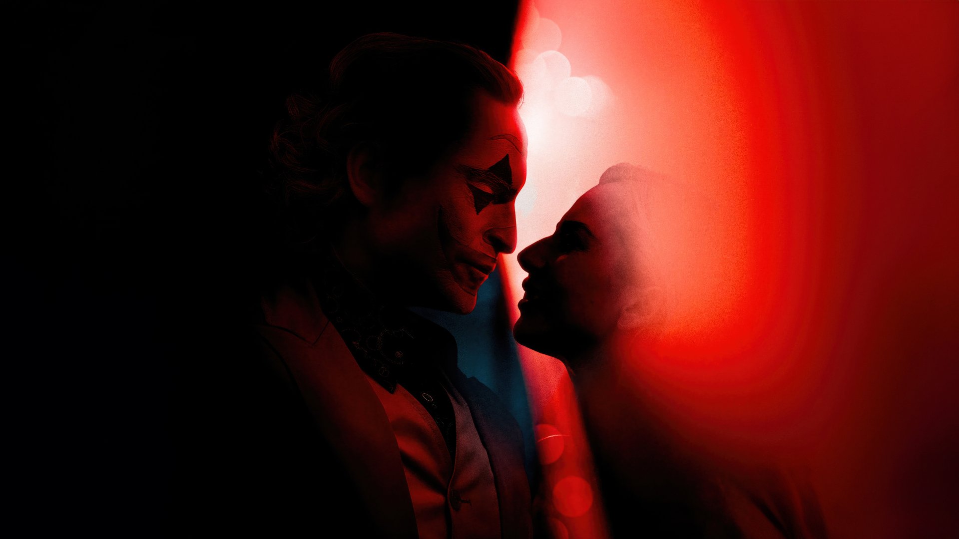 HD desktop wallpaper featuring a stylized artistic representation related to the movie Joker: Folie à Deux, depicting two silhouettes with Joker-like makeup in red and black tones, facing each other intimately against a dark background.