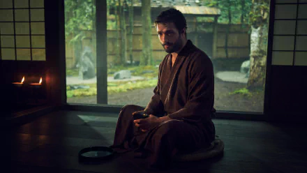 HD wallpaper featuring a contemplative scene from the TV show Shogun (2024) with a character in traditional attire sitting in a serene Japanese room overlooking a garden.