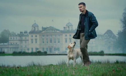 Actor from The Gentlemen (2024) TV show walking with a dog in front of an elegant manor house, available as HD desktop wallpaper and background.