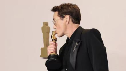 High-definition wallpaper featuring a person posing humorously with an Academy Award statue at the Oscars event.