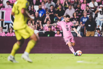 HD wallpaper of a soccer player from Inter Miami CF executing a pass during a match, featuring pink jerseys and fans in the background for desktop background.