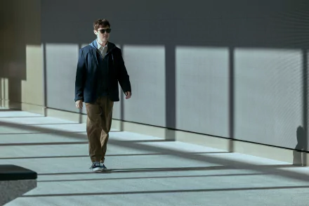 HD wallpaper featuring a scene from the TV show 'The Three-Body Problem' with a man walking through a well-lit, modern corridor, creating a dramatic play of light and shadow.