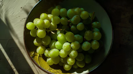 A close-up of fresh green grapes in a bowl, beautifully illuminated, creating a vibrant and refreshing HD desktop wallpaper background. 