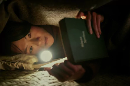 A person under a blanket with a book titled '3-Body Problem' illuminated by flashlight — HD wallpaper from the TV show adaptation.
