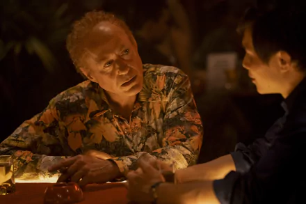 A still from the TV show The Sympathizer featuring two characters having a serious conversation at a dimly lit table, suitable as an HD desktop wallpaper.