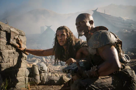 HD wallpaper featuring two characters from the movie 'Rebel Moon - Part Two: The Scargiver' crouching behind rubble with tense expressions, hinting at a dramatic moment in a desolate, war-torn setting.